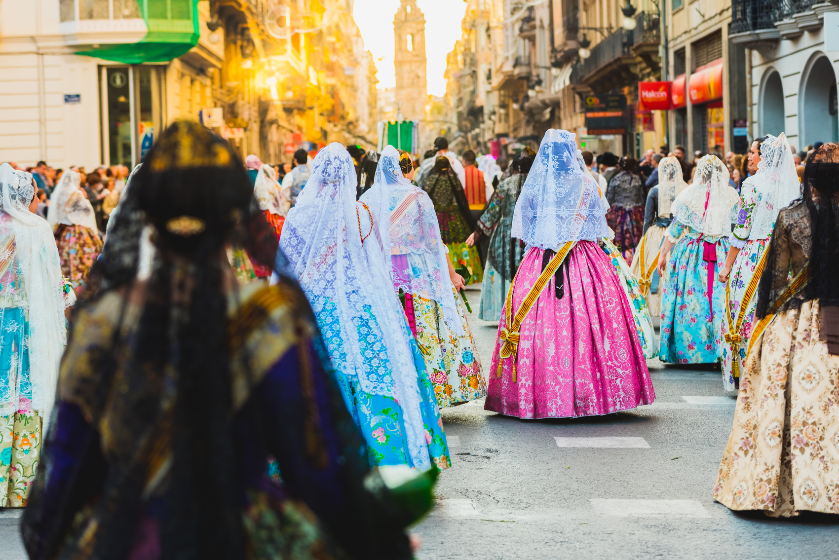 Valencia, Spain – March 17, 2019: Several of the thousands of women Falleras who parade down the street of La Paz with their typical Valencian Spanish dresses during the offering of Fallas to the Virgin, seen from behind.